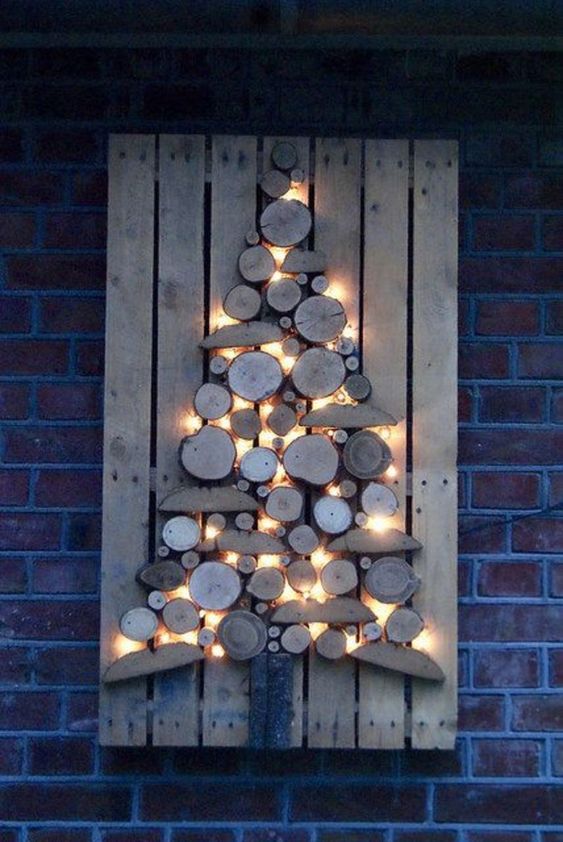 an outdoor Christmas tree on the wall, composed of tree and branch slices and lights is a very creative rustic decor idea