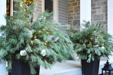 black planters with evergreen arrangements and lights plus candle lanterns will make your front porch look festive