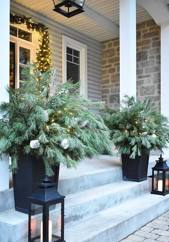 black planters with evergreen arrangements and lights plus candle lanterns will make your front porch look festive