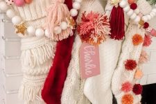 white stockings decorated with pink, burgundya nd rust pompoms and matching garlands for Christmas