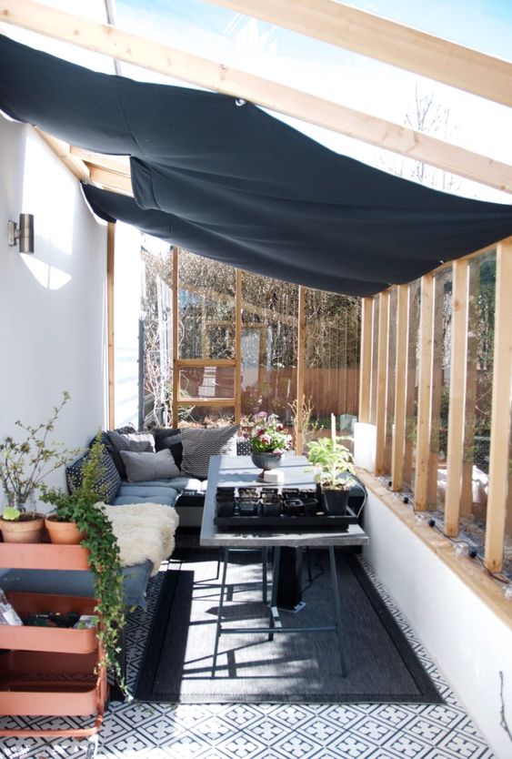 a Scandinavian sunroom, with concrete and metal furniture, potted greenery and plants and a cover to avoid excessive sunshine