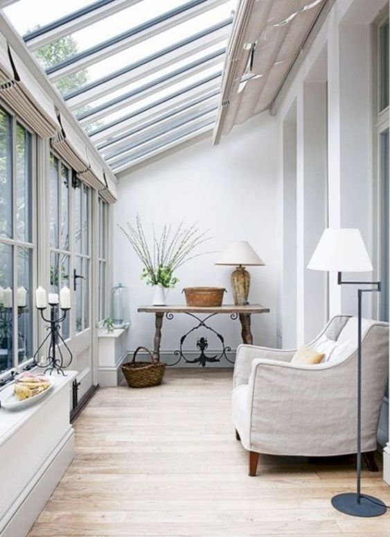 a chic vintage sunroom space with a neutral chair, a wooden table and some elegant lamps