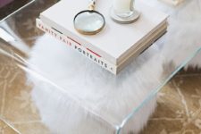 a clear acrylic coffee table with two faux fur stools under it – they are seen, which makes them part of the decor