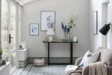a neutral and peaceful sunroom with a tiled floor and chic furniture plus stylish artworks