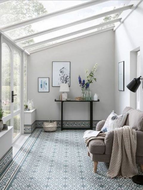 a neutral and peaceful sunroom with a tiled floor and chic furniture plus stylish artworks