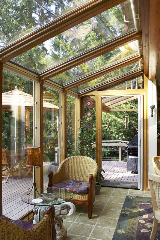 a refined vintage sunroom with rattan chairs, a glass table and a lamp is opened to the terrace