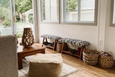 a restraint neutral boho sunroom with a grey sofa and a pouf, some printed upholstery and textiles, woven baskets and a lantern