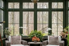 a vintage sunroom with dark rattan furniture, potted plants and blooms and a vintage pendant lamp