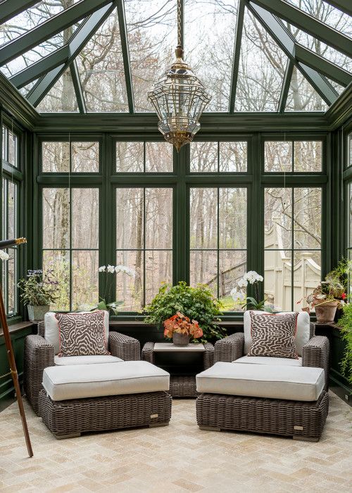 a vintage sunroom with dark rattan furniture, potted plants and blooms and a vintage pendant lamp