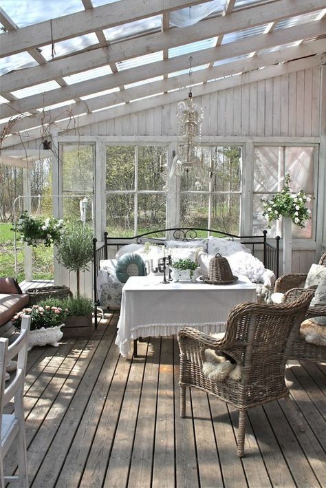 an elegant shabby chic sunroom with rattan chairs, a forged bed, potted greenery and blooms