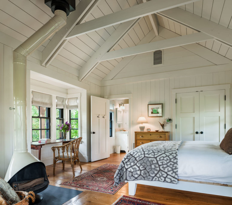 a farmhouse bedroom in neutral shades, with a home office nook by the window and ceiling beams  (Reed Axelrod Architects)