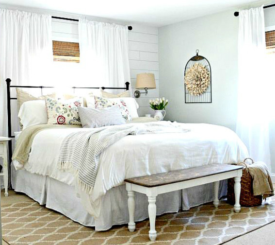 a vintage farmhouse bedroom done in creamy shades, a vintage bench and a forged bed plus vintage lamps on the wall  (SuperiorLinensHandmade)