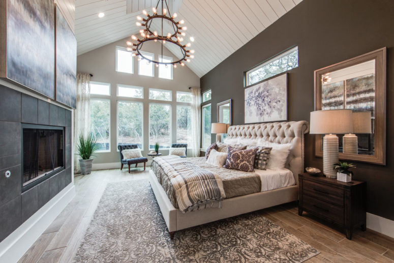 a contemporary farmhouse bedroom with an attic white ceiling, dark walls and a dark clad fireplace and a glazed wall  (Olinova Design)