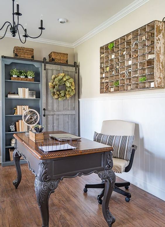 a French farmhouse home office with a built-in blue storage unit, a vintage desk, a leather chair and a storage unit on the wall