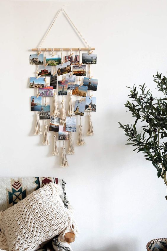 a boho wall hanging with tassels and photos hanging on ropes and macrame on it is very cool to DIY