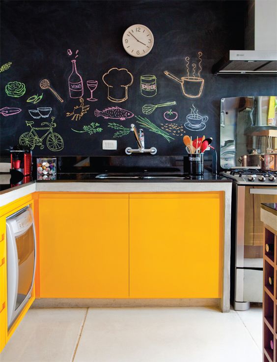 a bright kitchen in yellow with chalkboard walls that create a contrast and make the space look catchy and bold thanks to colorufl art