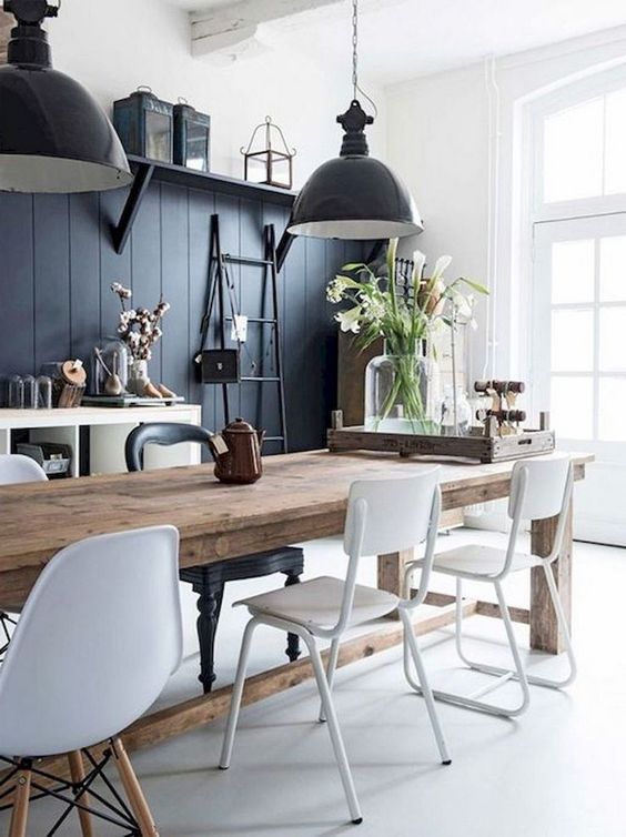 a contrasting monochromatic dining area with a black wall, a wooden table, white chairs, black pendant lamps