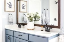 a cozy farmhouse bathroom with a serenity blue vanity, a tub, a large mirror and black fixtures for a more dramatic look