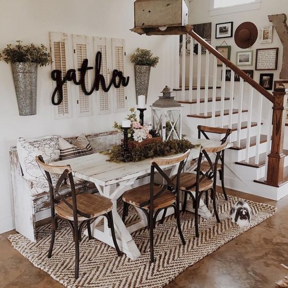 a cozy farmhouse dining area with a whitewashed table, wooden chairs, shutters, metal planters