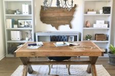 a cozy farmhouse home office with storage units, a wooden desk, a state wal art, a printed rug and a vintage chandelier