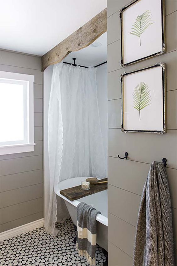 a cozy grey farmhouse bathroom with lace curtains, wood, grey planks on the walls and a mosaic tile floor