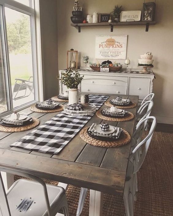 a cozy traditional farmhouse dining room with checked textiles, a wooden table, metal chairs and a buffet