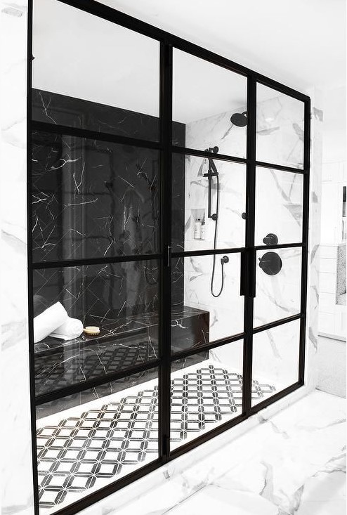a creative dramatic black and white shower space with black framed doors and a black marble wall plus a built-in bench