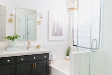 a light-filled farmhouse bathroom with a black vanity, gilded touches, white tiles and lamps