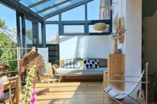 a mid-century modern sunroom with plywood and metal furniture, printed textiles and a dining space in the sun