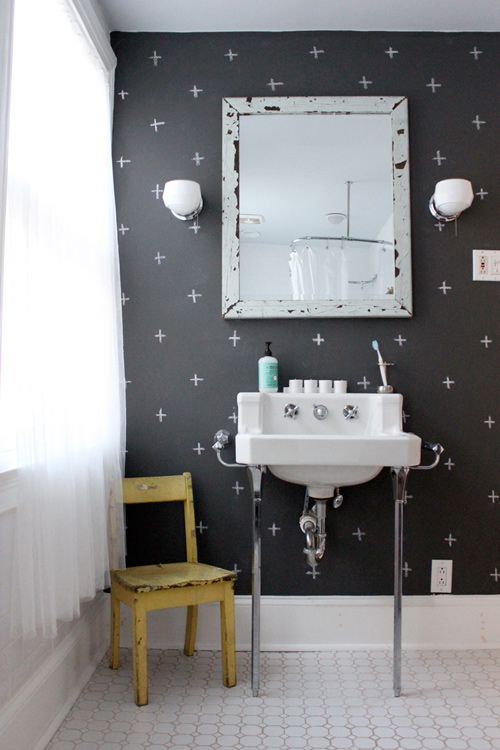 a modern black and white bathroom with a chalkboard accent wall, a wall-mounted sink, a mirror in a shabby chic frame and a yellow chair