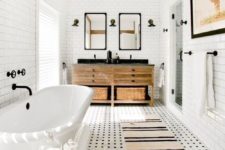 a modern farmhouse bathroom with black and white tiles on the floor, white ones on the wall, an oval tub and a wooden vanity