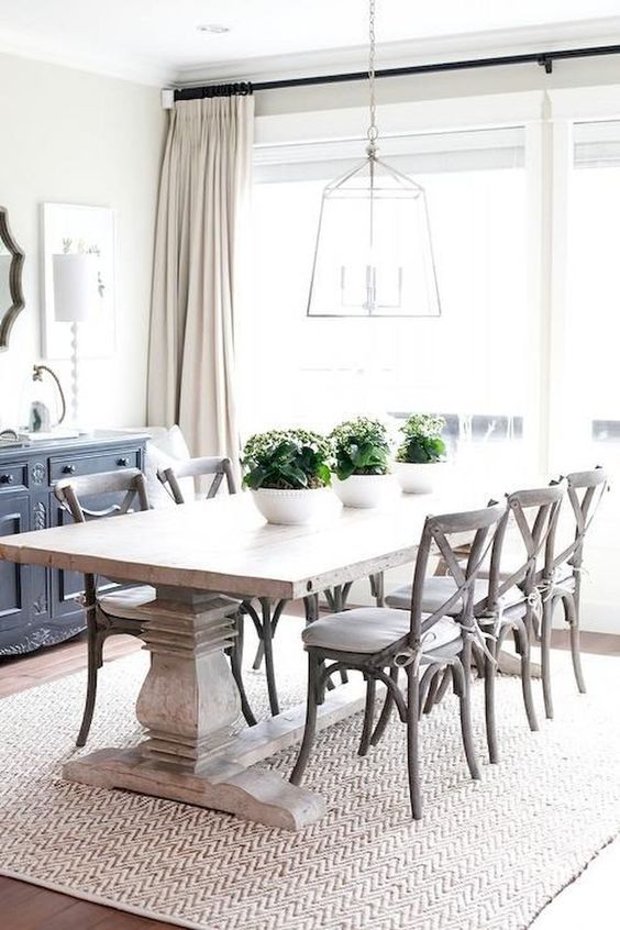 a modern farmhouse dining room with a whitewashed table, white chairs, a frame lamp and a buffet