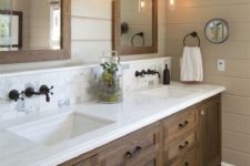 a modern farmhouse sink space with a large stained vanity, a marble top and wood framed mirrors