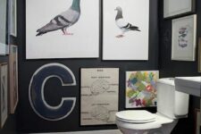 a modern powder room with chalkboard walls, a lot of artwork covering the walls, a wall-mounted sink and a printed rug