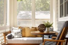 a modern sunroom with a white sofa, a grey chair, lanterns, a round coffee table is a lovely nook to relax