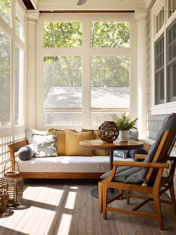a modern sunroom with a white sofa, a grey chair, lanterns, a round coffee table is a lovely nook to relax