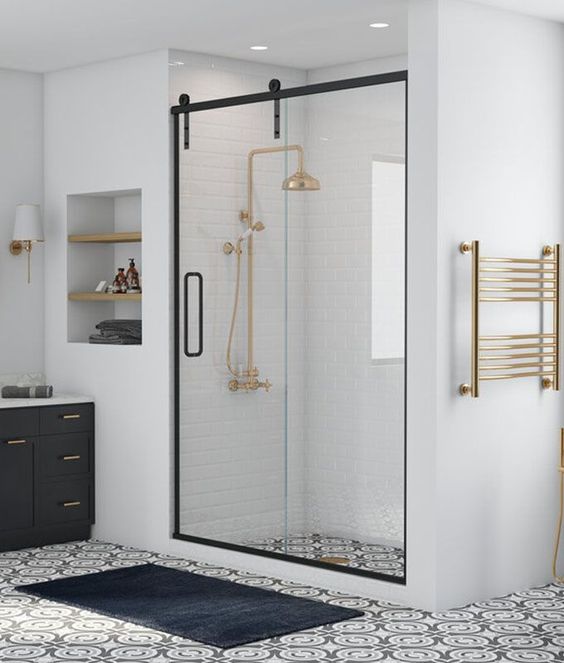 a monochromatic farmhouse bathroom with white and printed tiles, a shower space with a sliding glass door with a frame and a black vanity