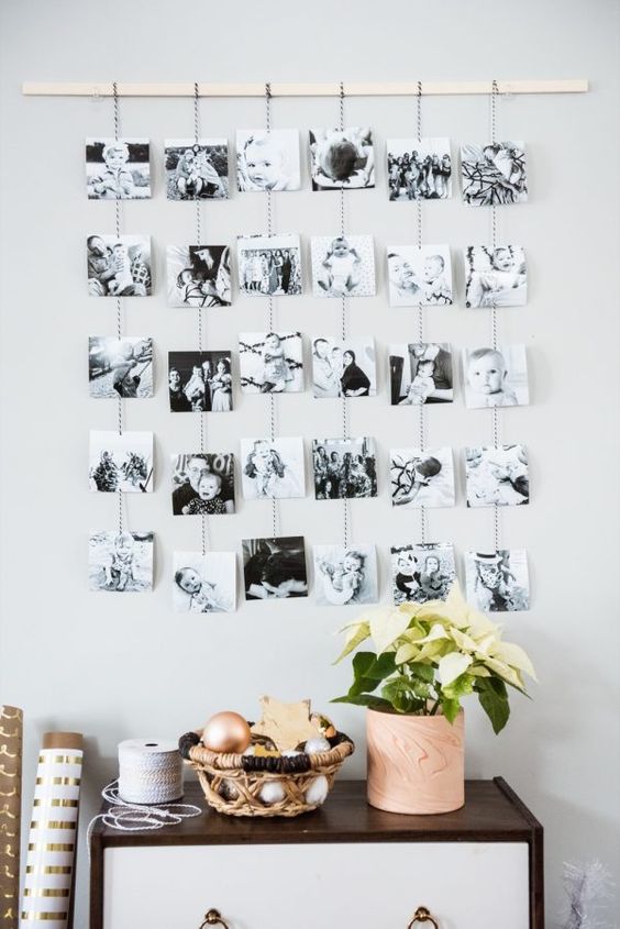 a photo display with a wooden rail and black and white photos on yarn hanging down is a lovely idea