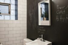 a powder room with a chalkboard accent wall, white tiles, a wall-mounted sink,a  toilet and a bubble chandelier