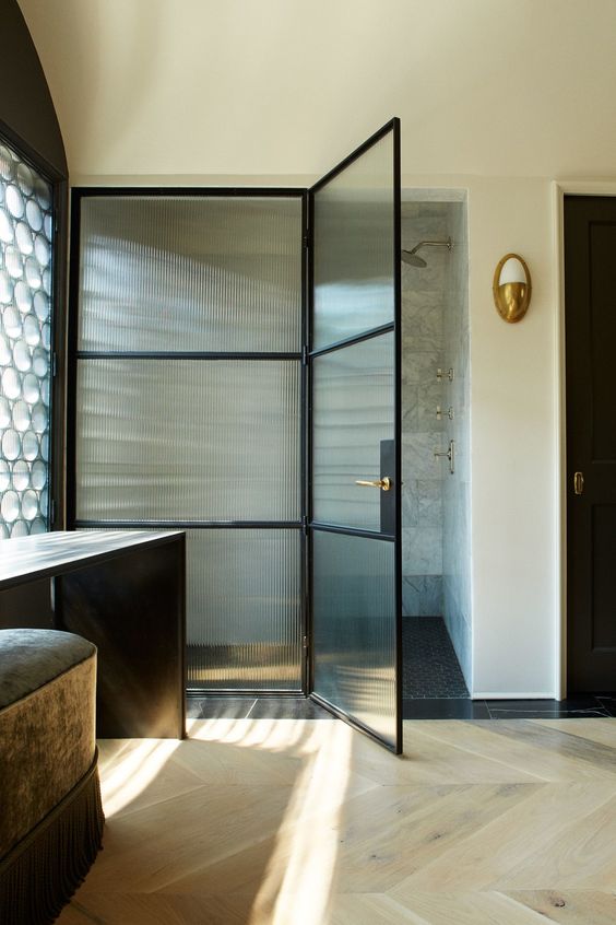 a refined bathroom with black furniture, a shower space with ribbed glass and black frame doors is pure chic