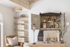 a refined farmhouse home office with a wooden desk, vintage chairs, a storage niche and open shelves is welcoming