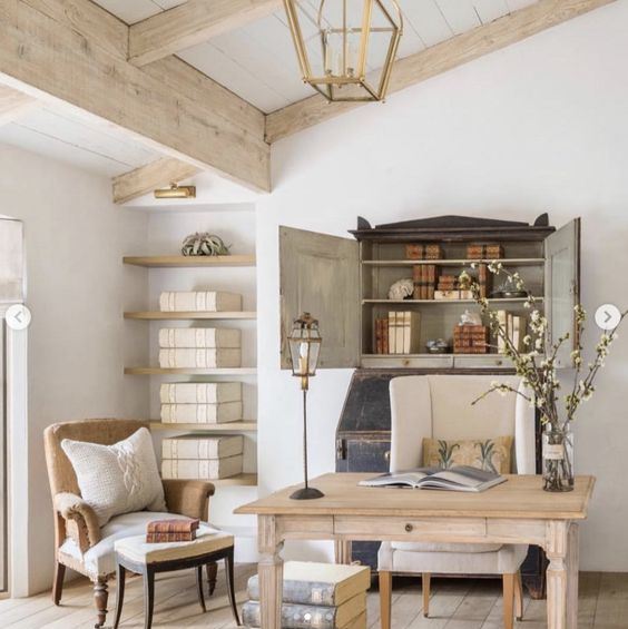 a refined farmhouse home office with a wooden desk, vintage chairs, a storage niche and open shelves is welcoming
