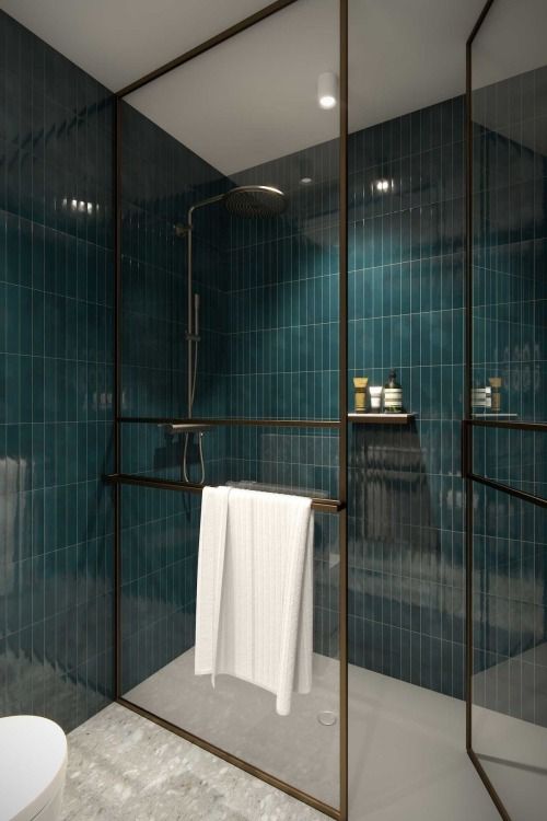 a shower space done with teal skinny tile, with black framed doors and a white floor is a bold and contrasting space