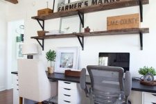 a simple farmhouse home office with industrial shelves, a shared desk, modern chairs and some potted greenery