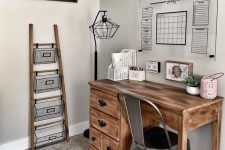 a small and cozy farmhouse home office with a wooden desk, a metal chair, a ladder and wire basket storage unit and an acrylic board