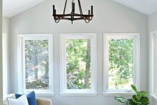 a small and cozy sunroom with neutral furniture, a couple of ottomans and some greenery feels like an additional living room
