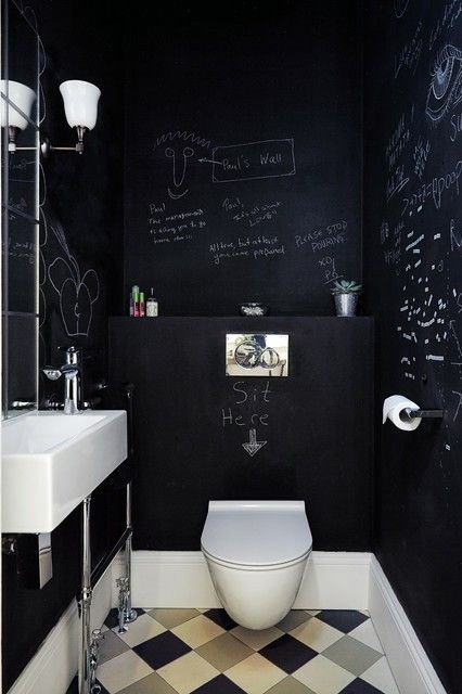 a small modern powder room with chalkboard walls, a wall-mounted sink, a toilet and a couple of sconces