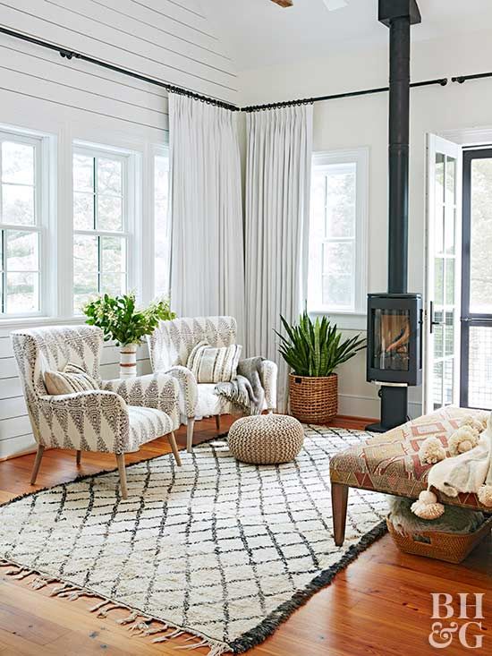 a stylish mid-century modern rustic sunroom with pritned textiles, chic furniture, potted greenery and a hearth
