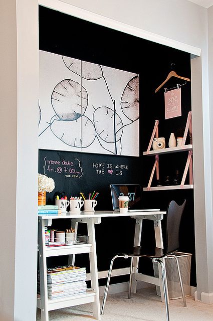 a tiny built-in home office with chalkboard walls, hanging shelves, some chalking, a small desk and a chair