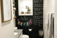 a tiny powder room with a chalkboard accent wall, a white vanity with a sink, a mirror with shutters, some decor and greenery
